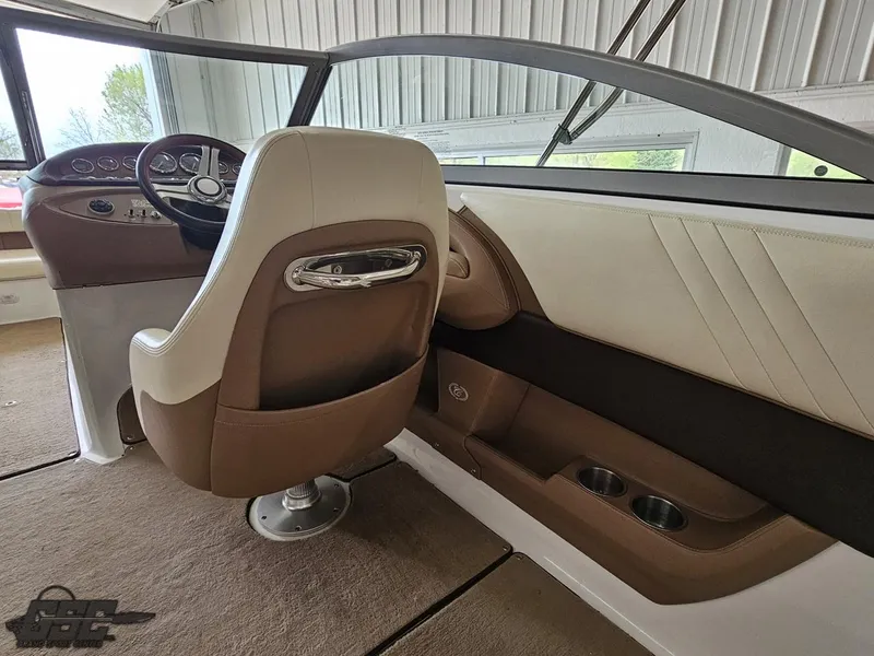 Slide: The Image of 2009 Cobalt 232 boat interior with beige and brown seating, steering wheel, and cup holders. - 31