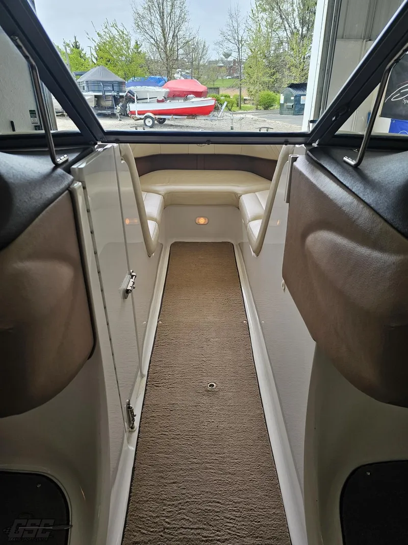 Slide: The Image of Interior view of a 2009 Cobalt 232 boat, featuring a carpeted walkway and seating area. - 46