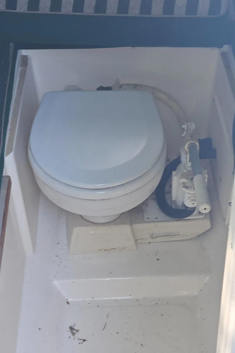 Slide: The Image of 1999 Pursuit 2460 Denali boat toilet, compact marine design, white interior. - 13