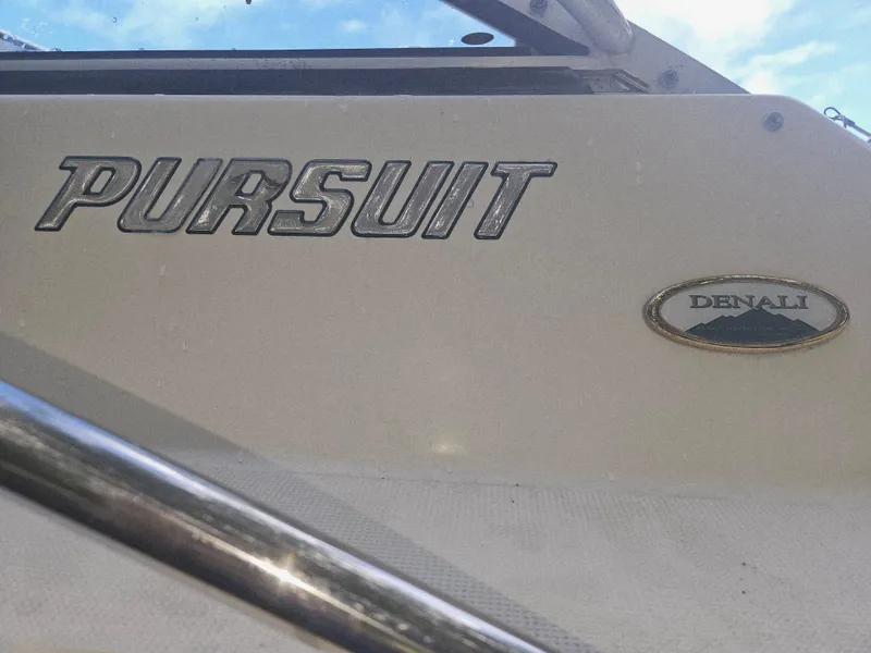 Slide: The Image of 1999 Pursuit 2460 Denali boat with logo and emblem detail. - 16