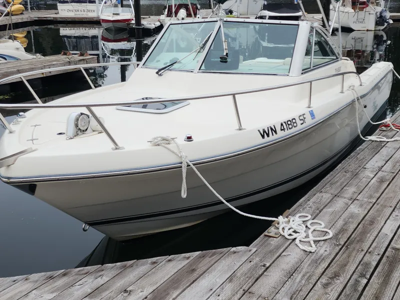 Slide: The Image of 1999 Pursuit 2460 Danali boat docked at marina, white exterior, moored with ropes. - 3