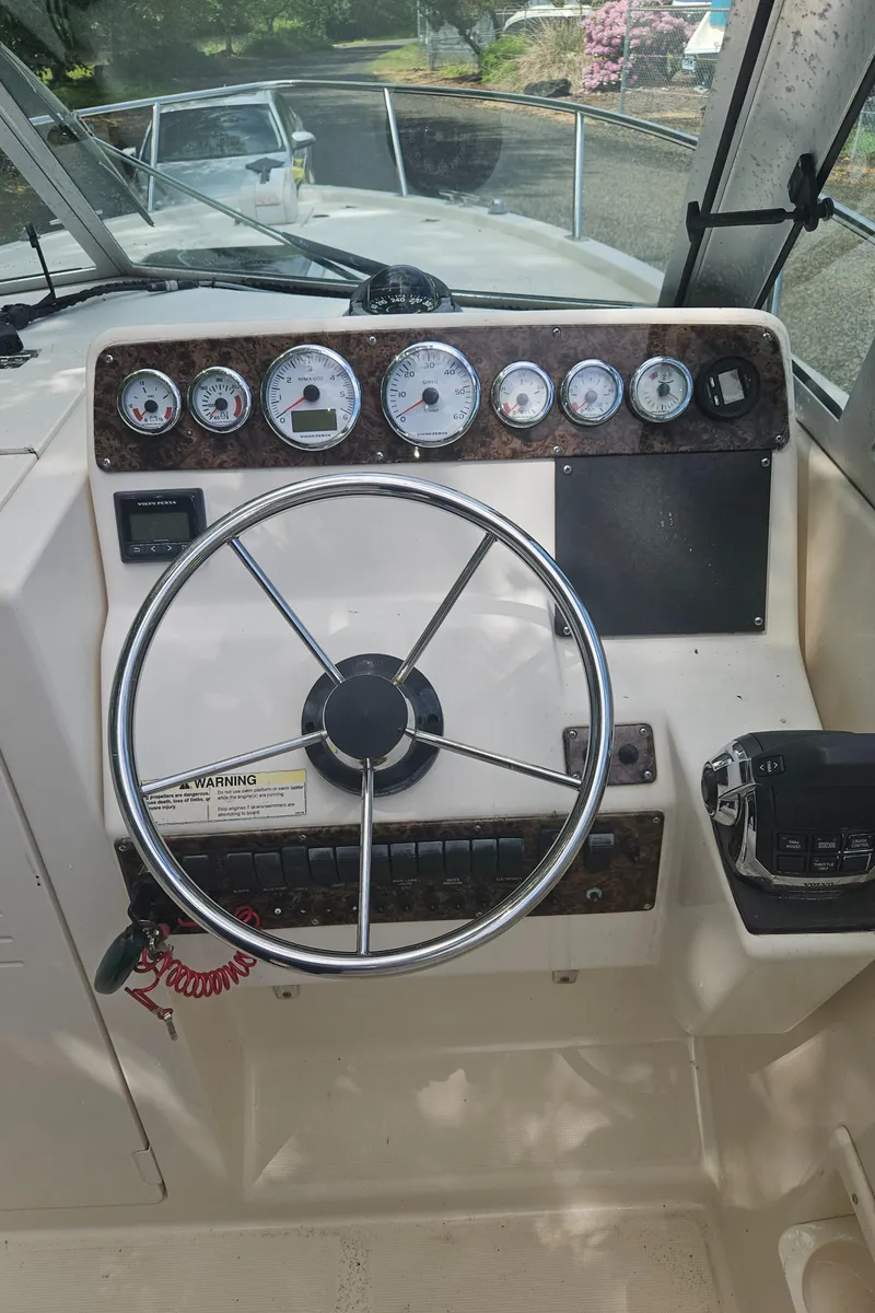 Slide: The Image of 1999 Pursuit 2460 Denali boat dashboard with steering wheel and gauges. - 6
