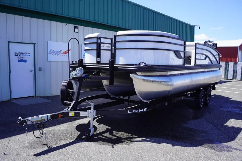 Slide: The Image of 2025 Lowe SS 210 DL pontoon boat on trailer outside a building. - 2
