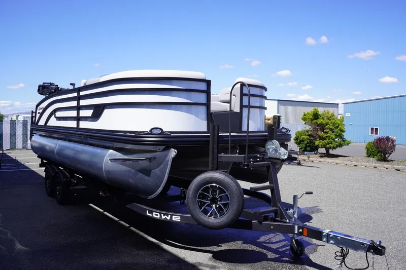 Slide: The Image of 2025 Lowe SS 210 DL pontoon boat on trailer, parked outdoors under blue sky. - 4