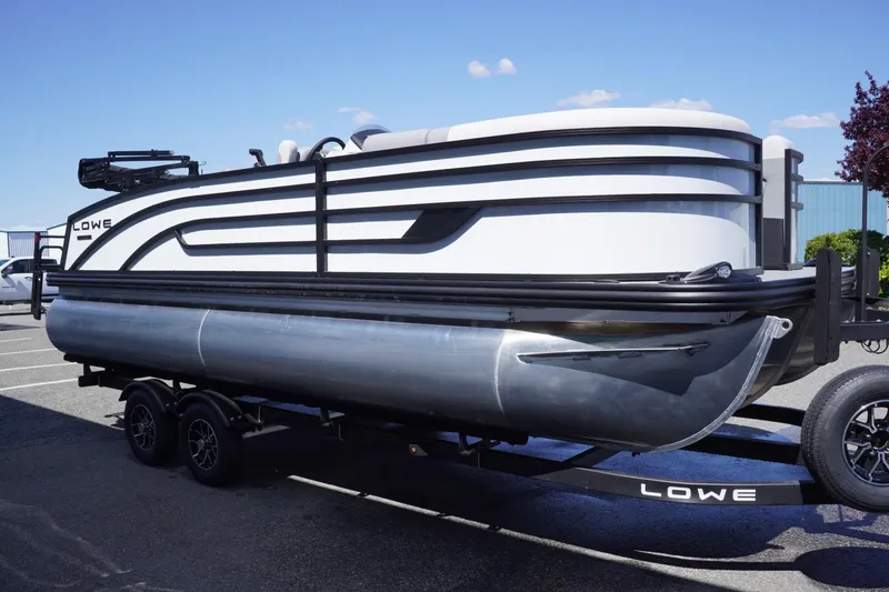 Slide: The Image of 2025 Lowe SS 210 DL pontoon boat on trailer, parked outdoors. - 5
