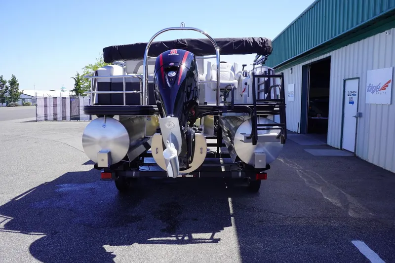 Slide: The Image of 2025 Lowe SS 210 DL pontoon boat, rear view, parked outside a green building. - 6