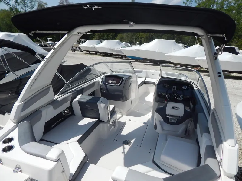Slide: The Image of 2019 Chaparral 230 Suncoast boat interior with seating and dashboard, docked outdoors. - 10