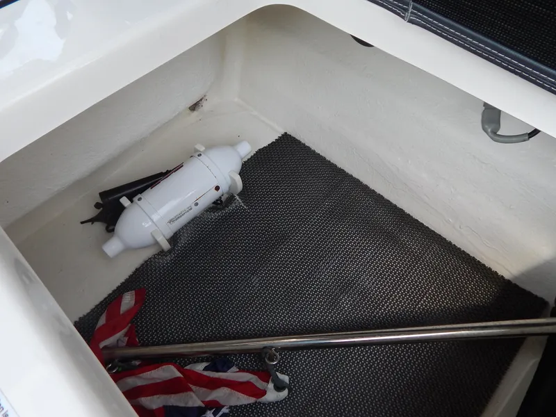 Slide: The Image of Storage compartment in 2019 Chaparral 230 Suncoast boat with safety equipment and flag. - 17