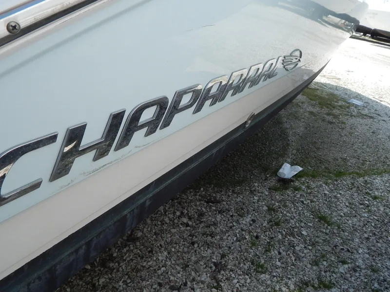 Slide: The Image of 2019 Chaparral 230 Suncoast boat logo on hull, parked on gravel surface. - 40