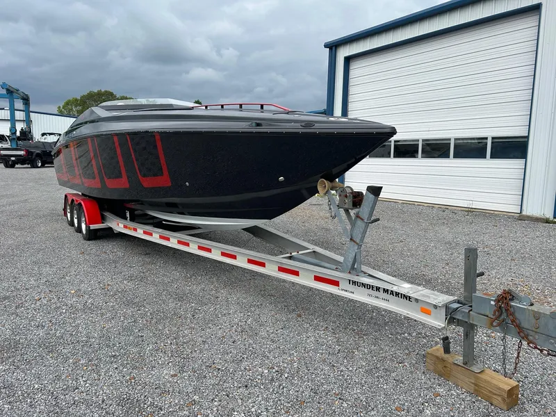 Slide: The Image of 2006 Baja Outlaw boat on trailer, parked outside a garage under cloudy skies. - 3
