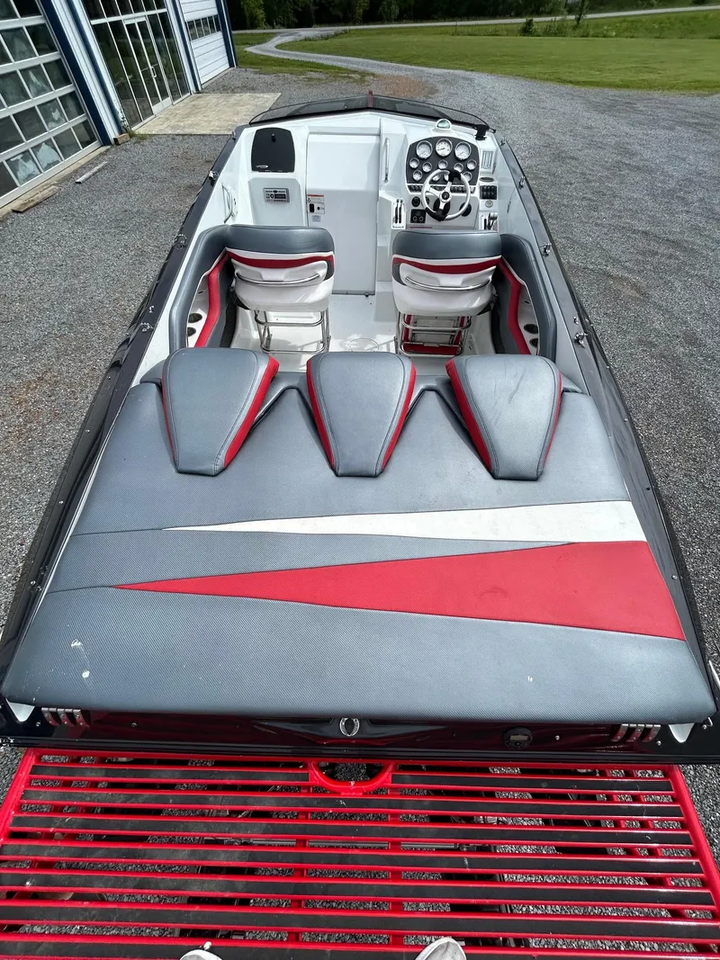 Slide: The Image of 2006 Baja Outlaw boat interior with red and gray seating, parked on gravel. - 7
