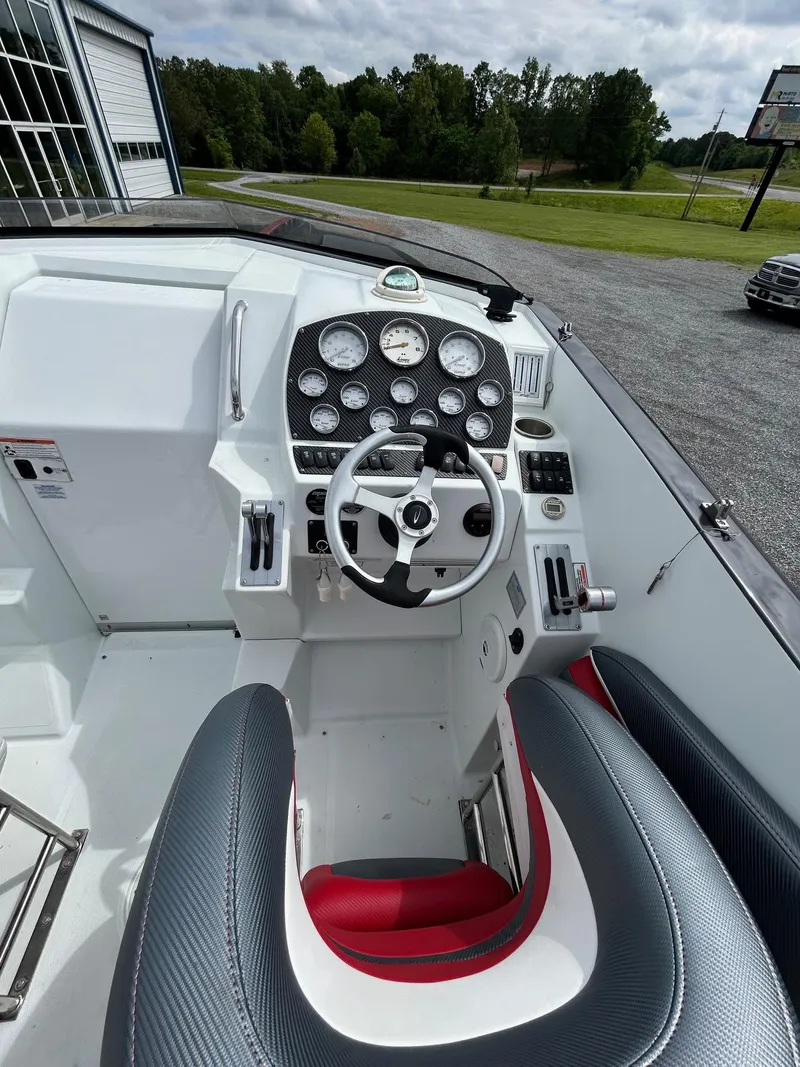 Slide: The Image of 2006 Baja Outlaw boat cockpit with steering wheel and gauges, parked outdoors. - 9
