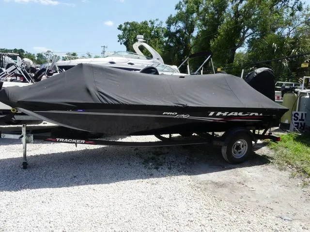 Slide: The Image of 2022 Tracker Pro 170 boat covered, parked on gravel with trees in the background. - 3