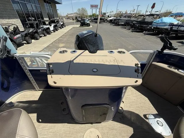 Slide: The Image of 2022 Bennington 23 SFXAPG boat interior with fishing station and motor, parked at dealership. - 23