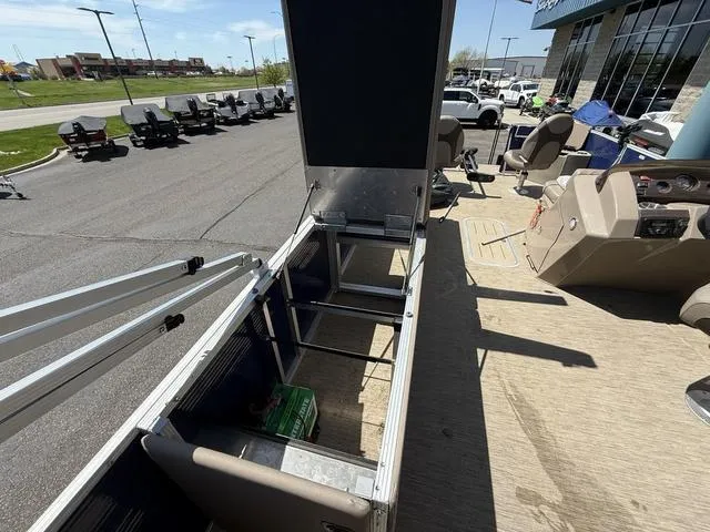 Slide: The Image of 2022 Bennington 23 SFXAPG pontoon boat with open storage compartment, displayed outdoors. - 28