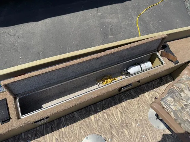 Slide: The Image of Open storage compartment in a 2000 Lund 1475 Rebel boat, showing equipment and wiring. - 10