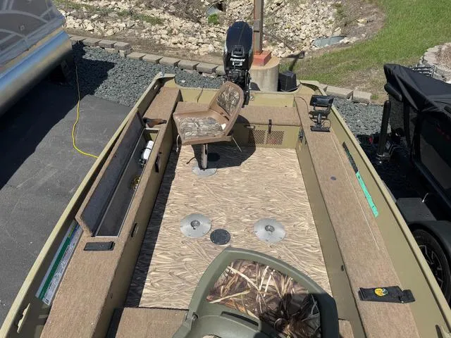 Slide: The Image of 2000 Lund 1475 Rebel boat interior with seating and motor, parked on a paved surface. - 15