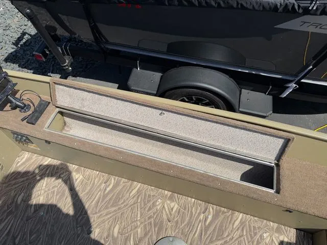 Slide: The Image of 2000 Lund 1475 Rebel boat interior with storage compartment and trailer in sunlight. - 17