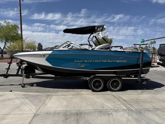 Slide: The Image of 2013 Nautique G23 boat on trailer, blue and white design, parked outdoors. - 5