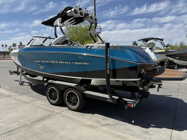 Slide: The Image of 2013 Nautique G23 boat on trailer, blue and black design, parked outdoors. - 6
