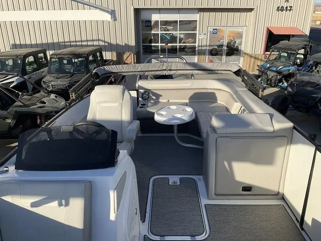 Slide: The Image of 2023 Hurricane FunDeck 2260 REF OB boat interior with seating and table, parked near vehicles. - 9