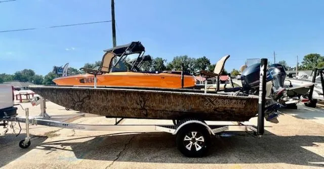 Slide: The Image of 2025 Xpress Boats HD 16 DB on trailer, parked outdoors, side view. - 6