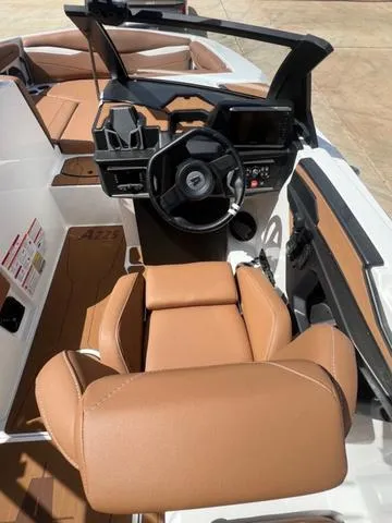 Slide: The Image of 2025 Axis Wake Research A225 boat interior with tan leather seating and modern dashboard. - 11