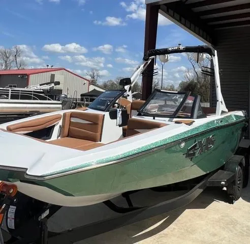 Slide: The Image of 2025 Axis Wake Research A225 boat with green exterior, docked under a clear blue sky. - 3