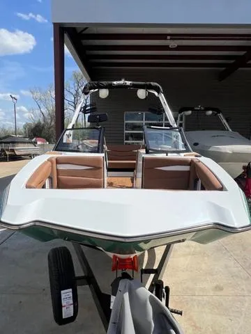 Slide: The Image of 2025 Axis Wake Research A225 boat with sleek design, parked outdoors under a canopy. - 4