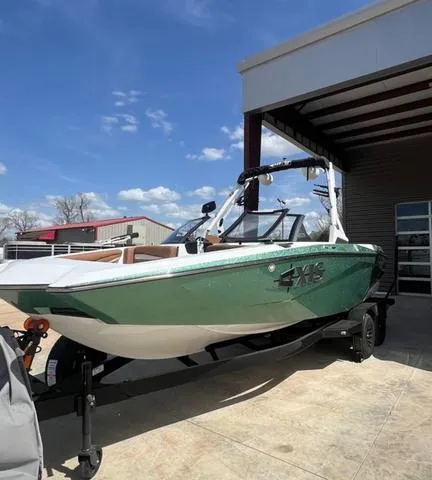 Slide: The Image of 2025 Axis Wake Research A225 boat in green, parked outdoors under a clear blue sky. - 5