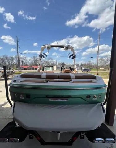 Slide: The Image of 2025 Axis Wake Research A225 boat, green and white, parked outdoors under a cloudy sky. - 7