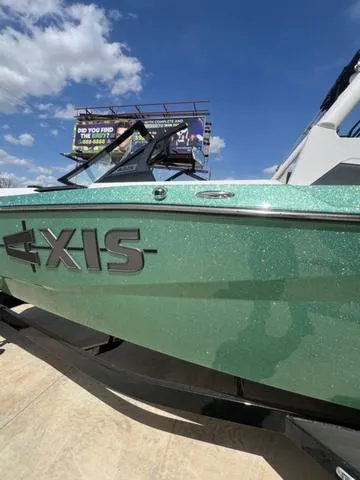 Slide: The Image of 2025 Axis Wake Research A225 boat with metallic green finish under a clear blue sky. - 8