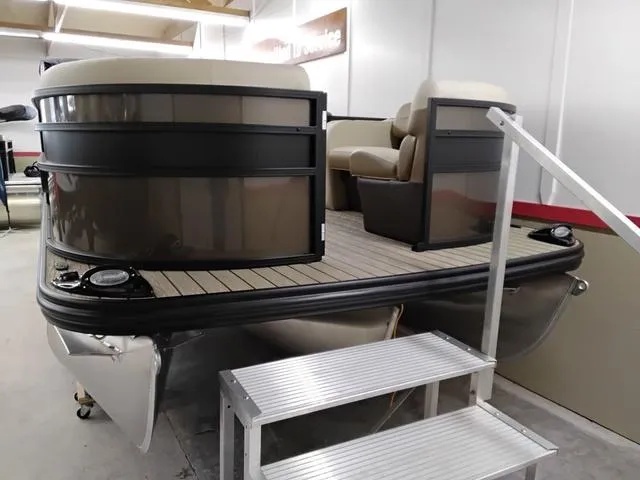 Slide: The Image of 2025 Lowe SS 210 TL pontoon boat in showroom with seating and boarding steps. - 2