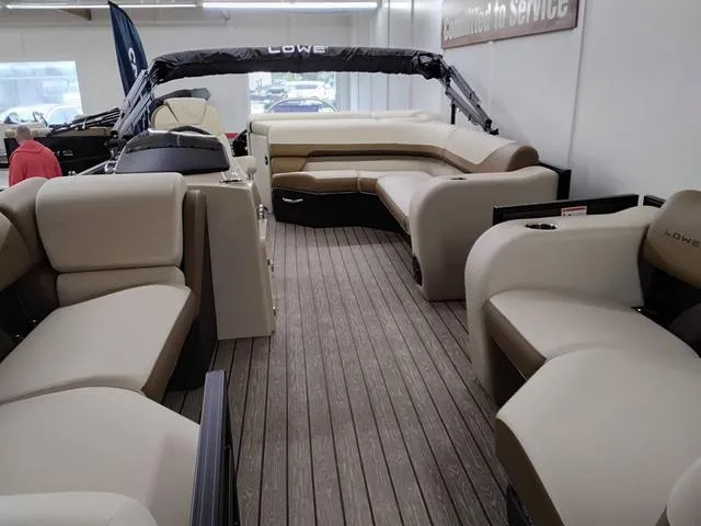 Slide: The Image of 2025 Lowe SS 210 TL pontoon boat interior with beige seating and wood-style flooring. - 3