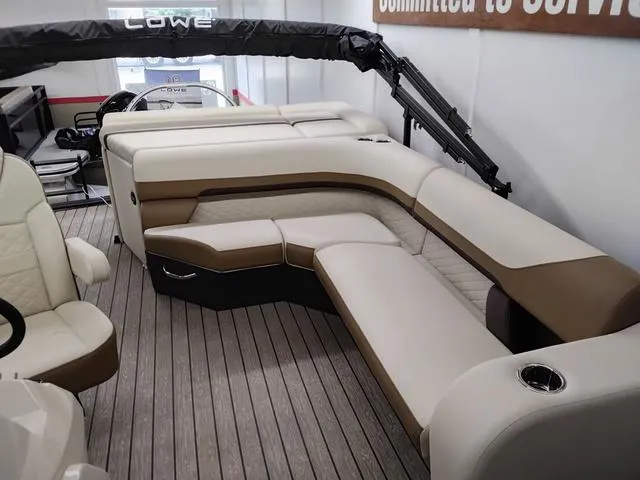 Slide: The Image of 2025 Lowe SS 210 TL pontoon boat interior with beige and brown seating on wooden deck. - 4