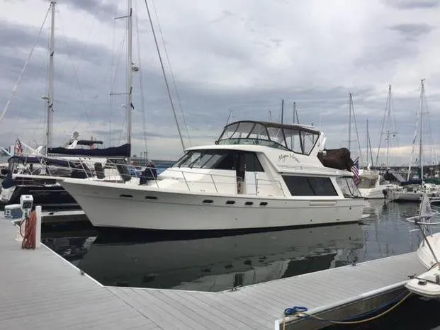 Slide: The Image of 1996 Bayliner 4788 yacht docked at marina, surrounded by sailboats under cloudy sky. - 0