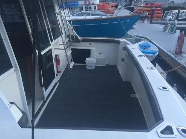 Slide: The Image of 1996 Bayliner 4788 yacht deck with ladder and docked boats in the background. - 17