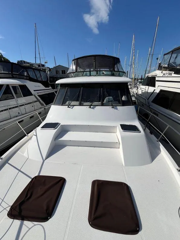 Slide: The Image of 1996 Bayliner 4788 yacht docked, showcasing spacious deck and sleek design under clear blue sky. - 24