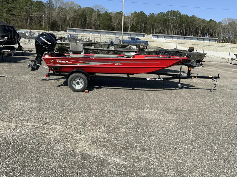 Slide: The Image of Red 2006 Triton 1546 SS boat with Mercury engine on trailer, parked outdoors. - 3