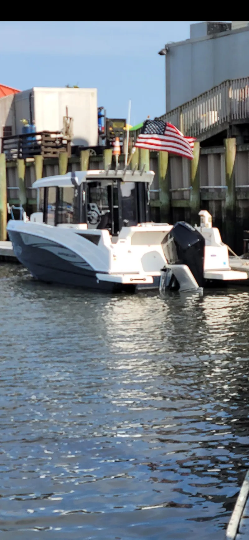 Slide: The Image of 2020 Beneteau Barracuda 8 boat docked, American flag, calm water, urban marina setting. - 10