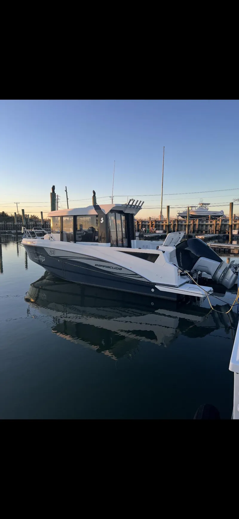 Slide: The Image of 2020 Beneteau BARRACUDA 8 boat docked at sunset, reflecting on calm water. - 2
