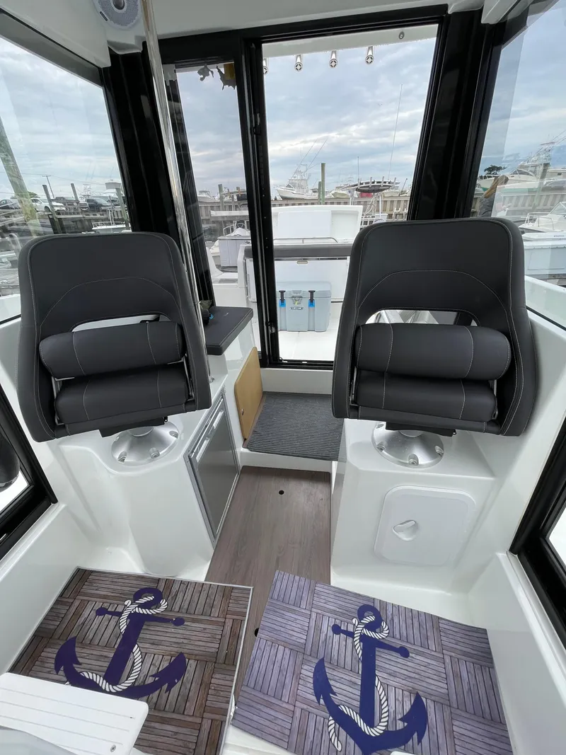 Slide: The Image of Interior of 2020 Beneteau BARRACUDA 8 with two black seats and nautical-themed mats. - 44