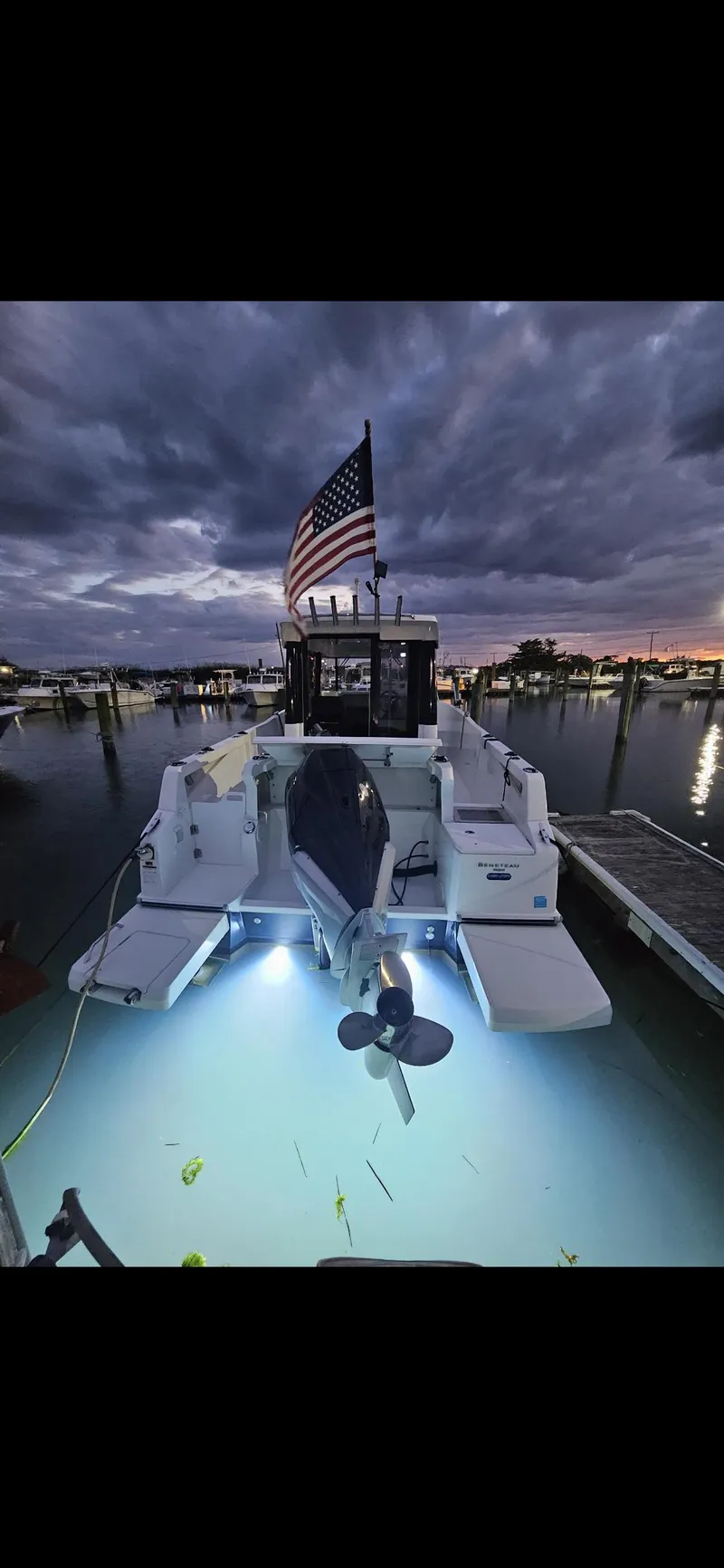 Slide: The Image of Beneteau BARRACUDA 8 boat docked at sunset with underwater lights and American flag. - 6