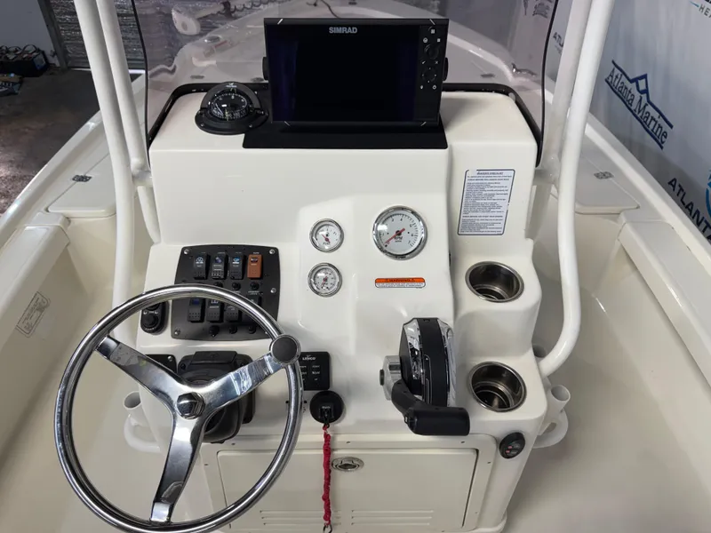 Slide: The Image of 2020 Mako 21 LTS boat console with steering wheel, gauges, and Simrad display. - 17