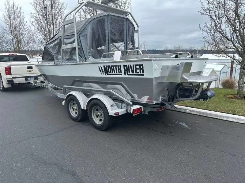 Slide: The Image of 2013 North River Commander boat on trailer, parked near trees and a white truck. - 4