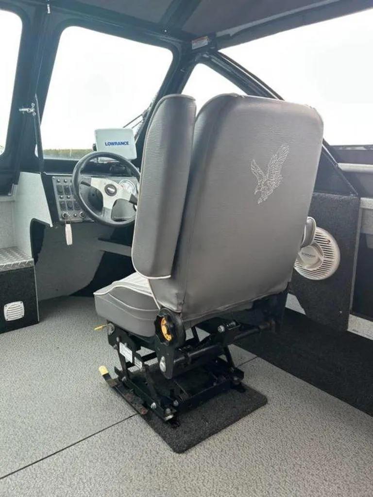 Slide: The Image of Interior of a 2013 North River Commander boat, featuring a captain's seat and steering console. - 5