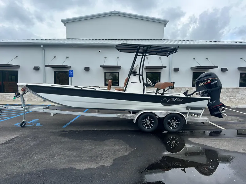 Slide: The Image of 2025 Avid 22 Recon boat on trailer, parked outside a building. - 14