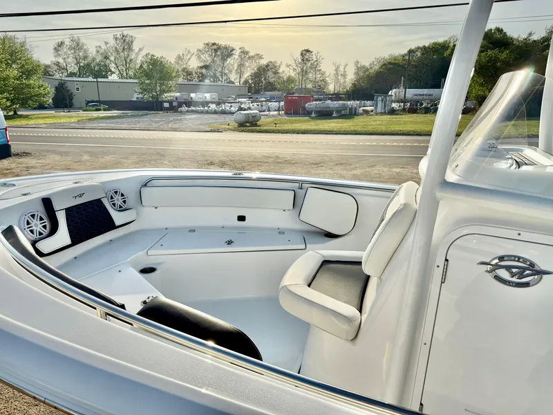 Slide: The Image of 2025 Tidewater 210 LXF boat interior with seating and speakers, parked outdoors. - 14