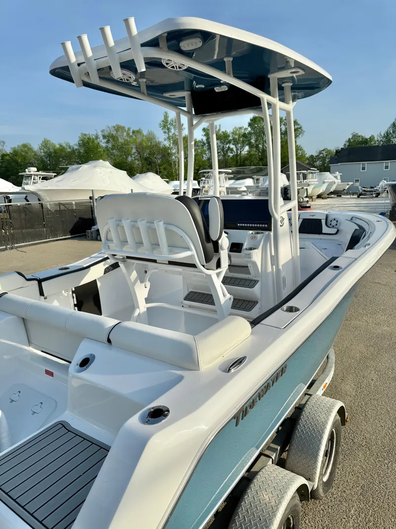 Slide: The Image of 2025 Tidewater 210 LXF boat with T-top and dual-axle trailer in a marina setting. - 20