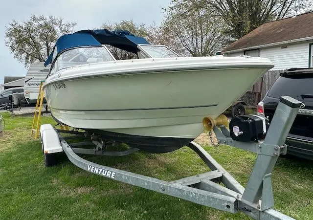 Slide: The Image of 2002 Bayliner 2150 boat on trailer, parked on grass near houses and trees. - 4